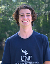 Headshot of student standing outdoors with nature background.