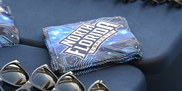 Sunglasses and microfiber cloths that say North Florida Esports