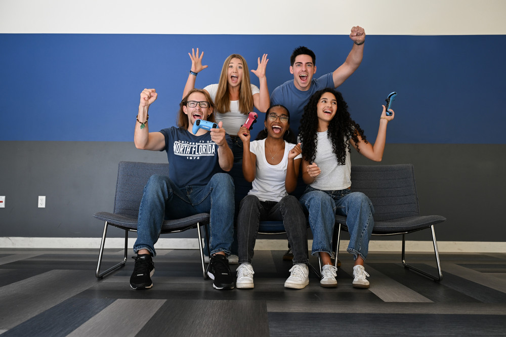 3 students holding controllers and 2 behind, all super excited