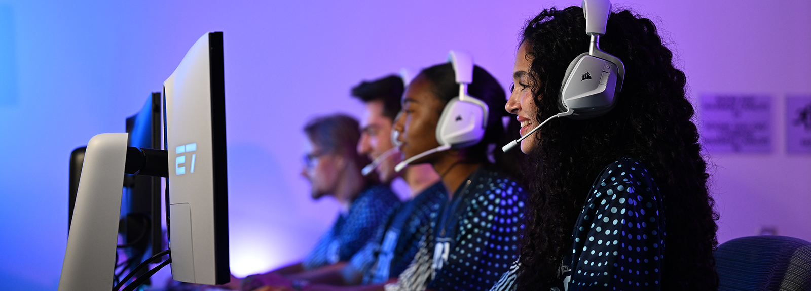Students wearing headphones gaming on desktops