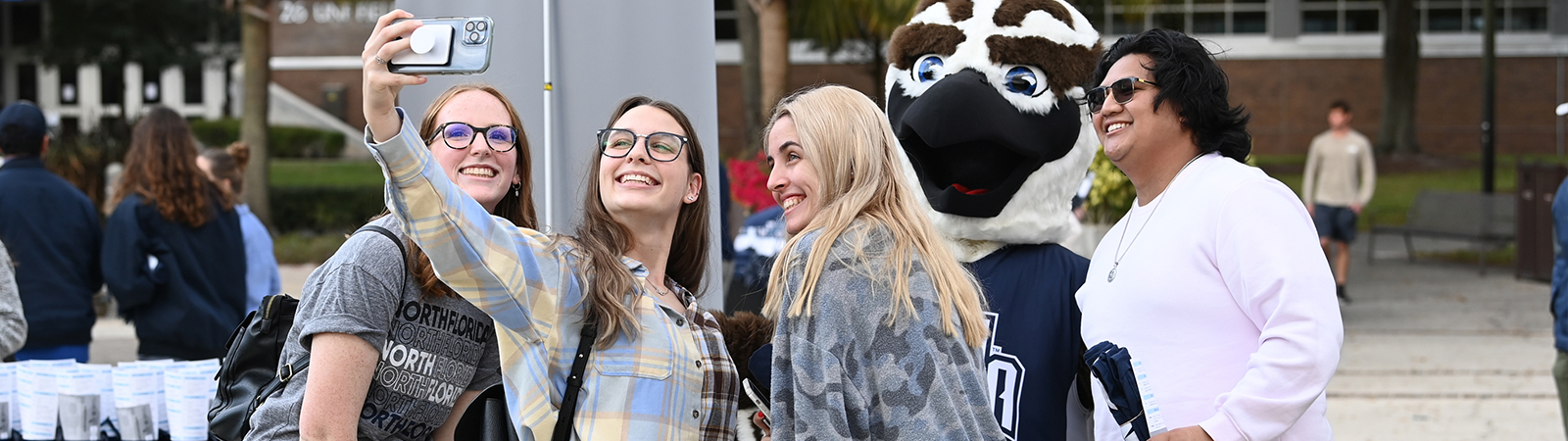 Group of four UNF student staking a selfie with Ozzie the Osprey