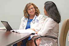 two medical professionals talking to each other at a table