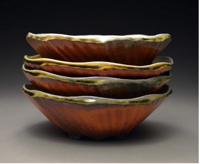 Stacked ceramic bowls glazed red with yellow and black lip