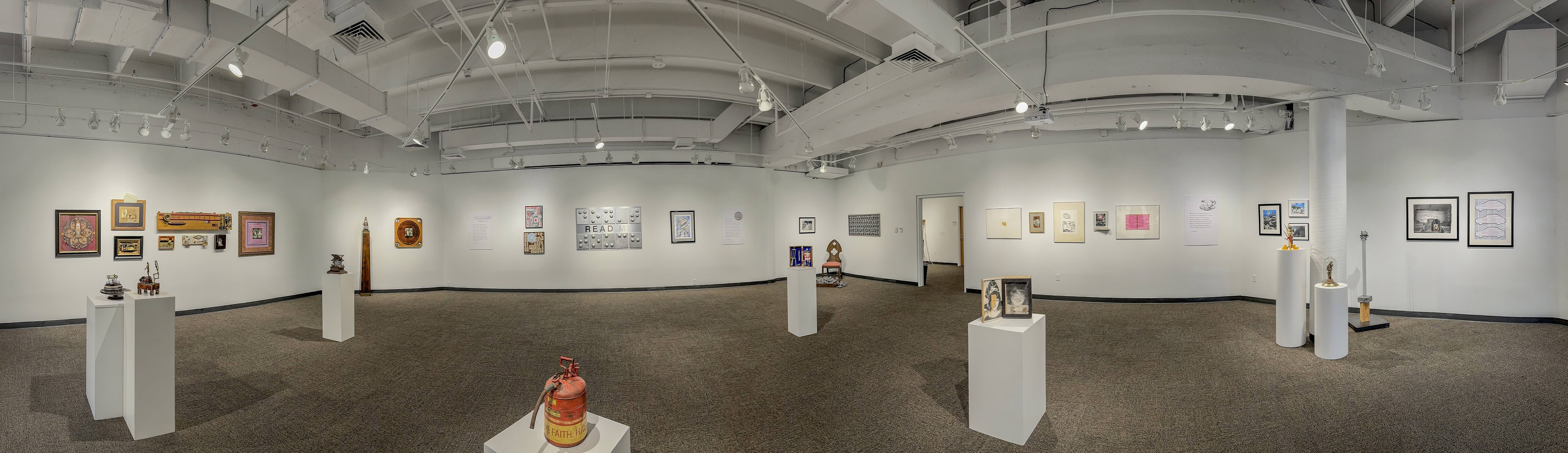 A panoramic view of an art gallery showcasing various artworks displayed on the walls and pedestals.