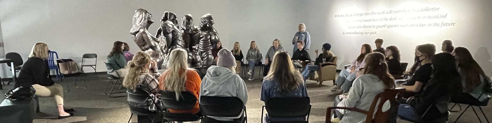 class sitting around a sculpture discussing art