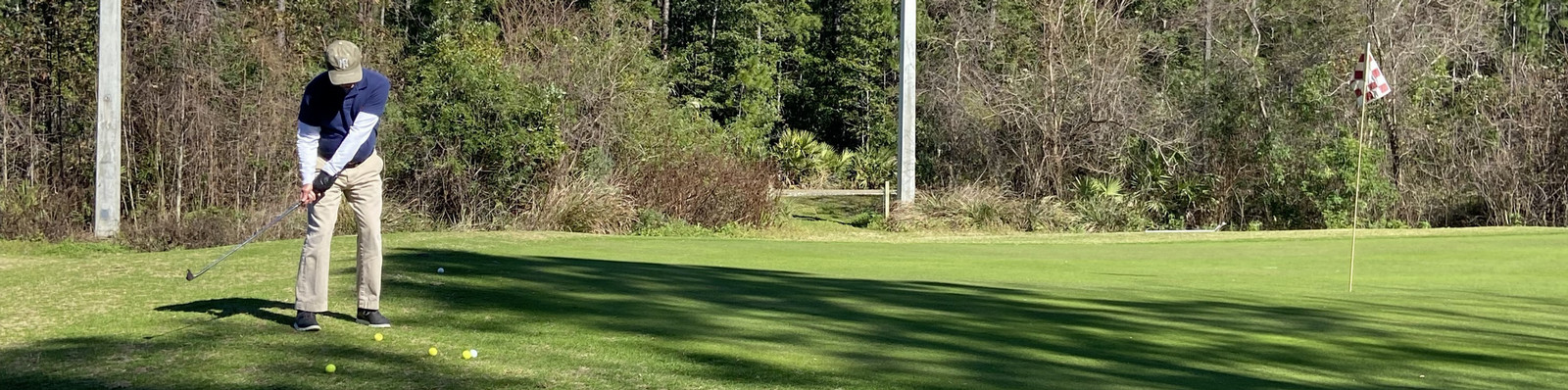 man hitting multiple balls on a green
