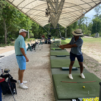 golf instructor and student driving club on driving range