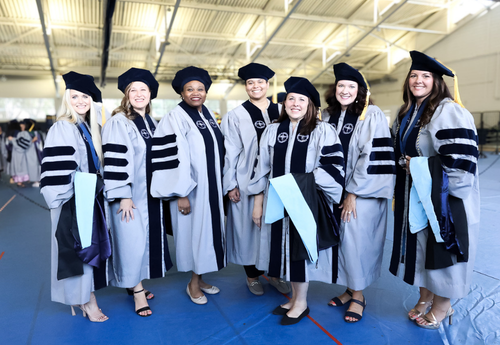 A group of Ed.D. students stand together in their graduation robes
