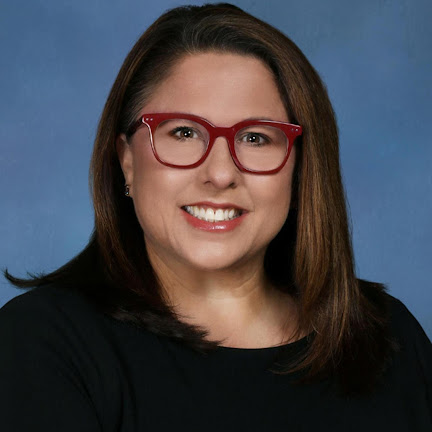 Heather Teto smiles in a photo with a blue backdrop