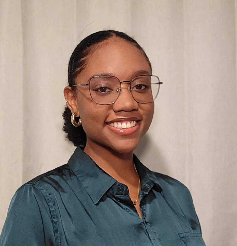 Smiling alumni headshot with a beige background 