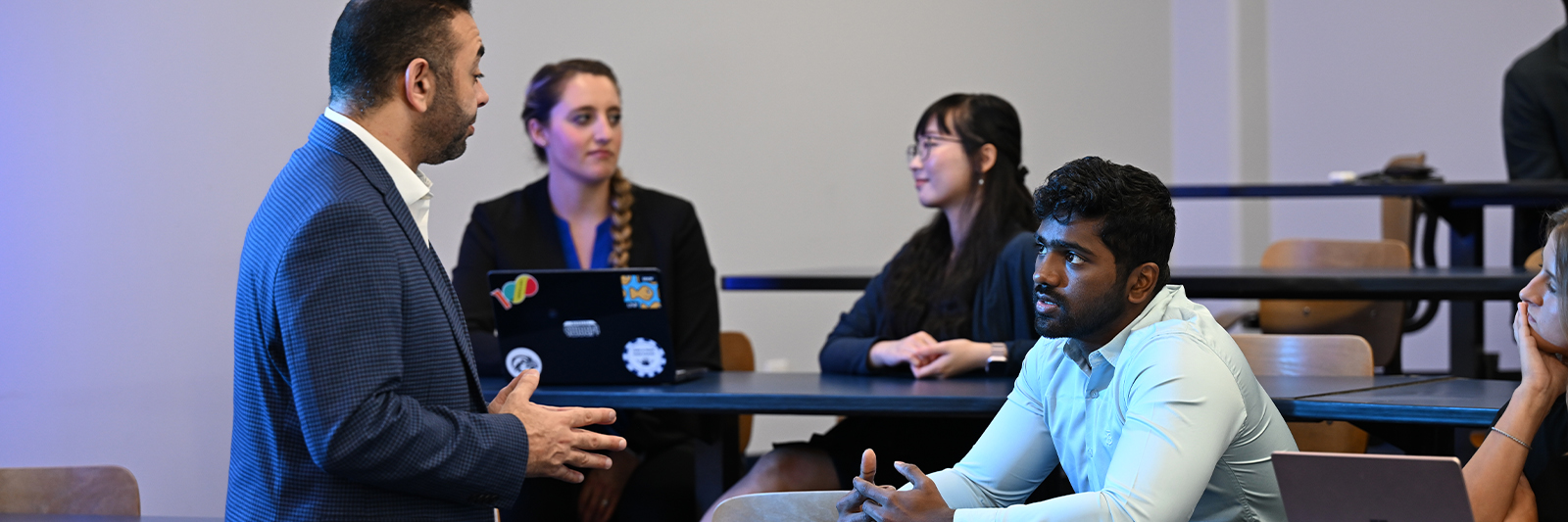UNF student and professor talking in a busy classroom