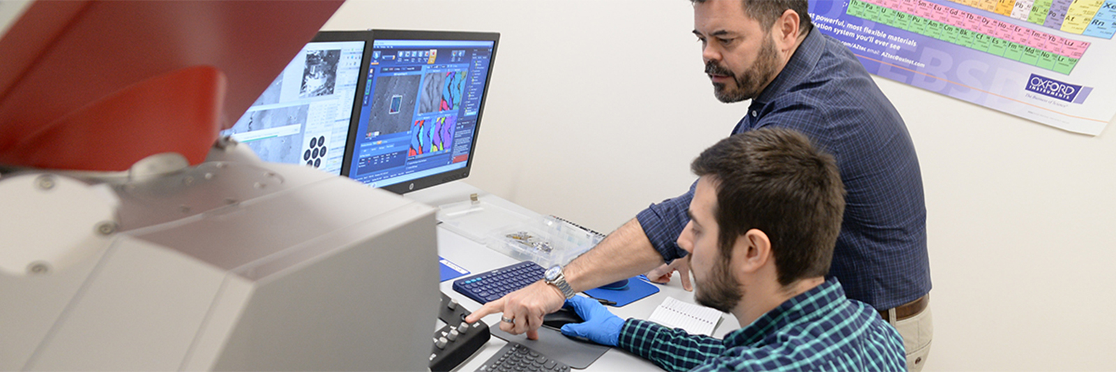 UNF student working on computer with professor standing directing