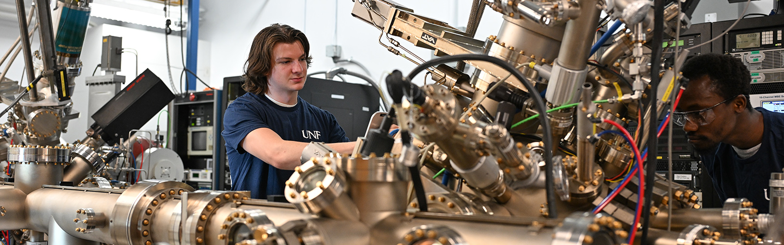 Two physics students working on large mechanical device