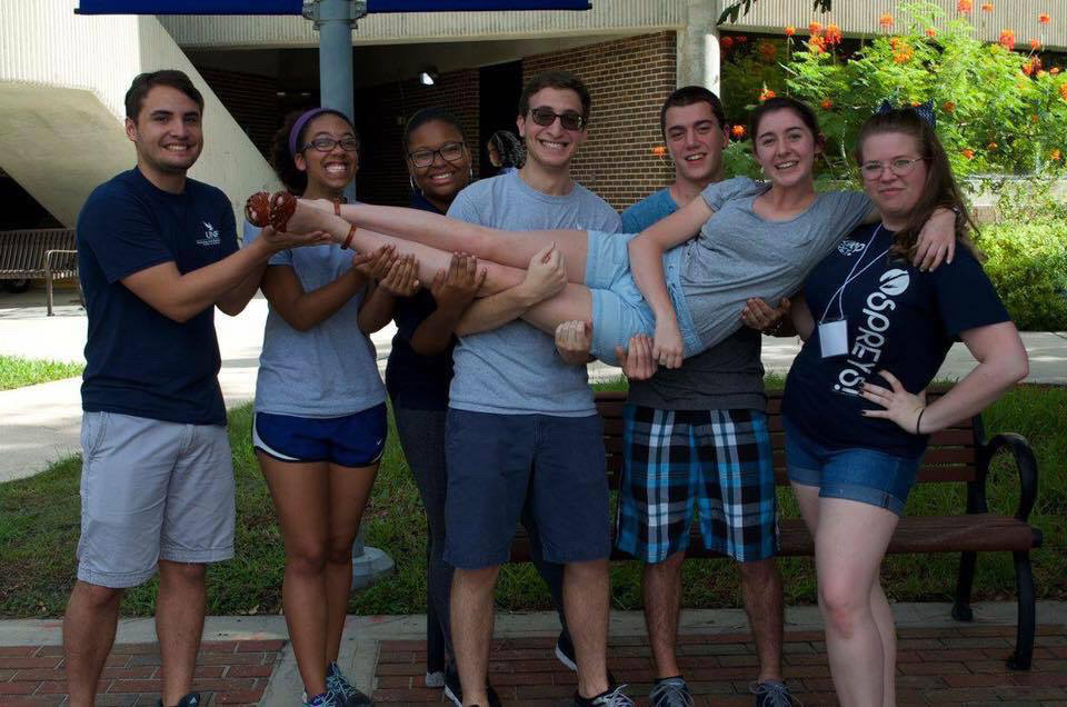 Damiana stands smiling with a group of classmates in the HEA program on UNF's campus.