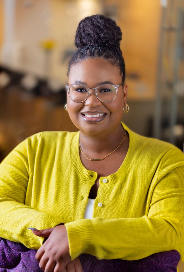 Damiana Sorrell smiles wearing a yellow cardigan.