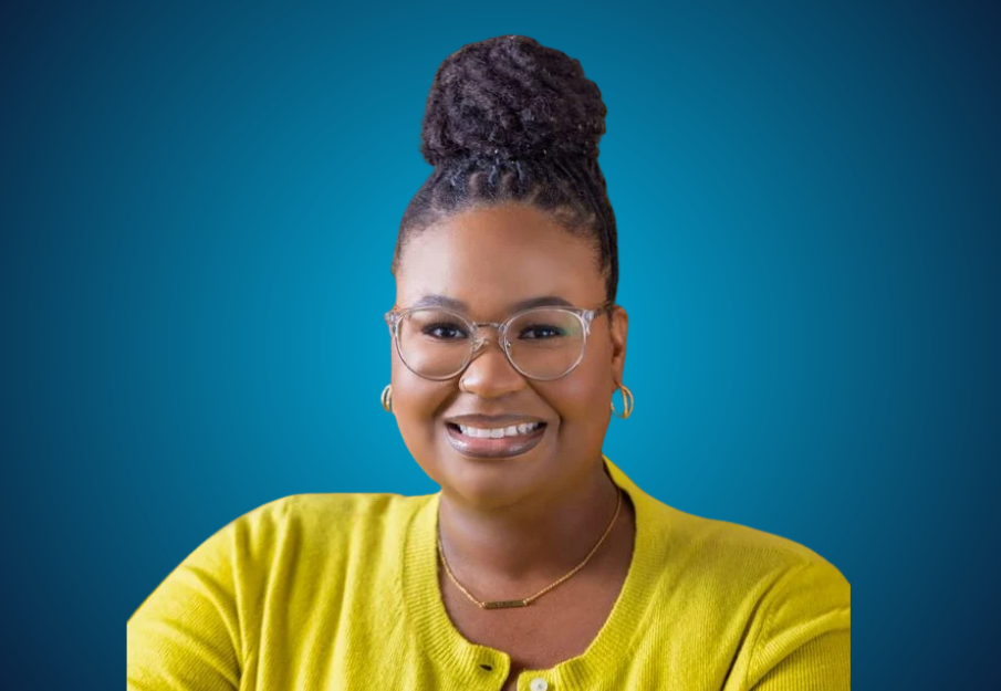 Damiana Sorrell smiles wearing a yellow cardigan in front of a blue gradient background.