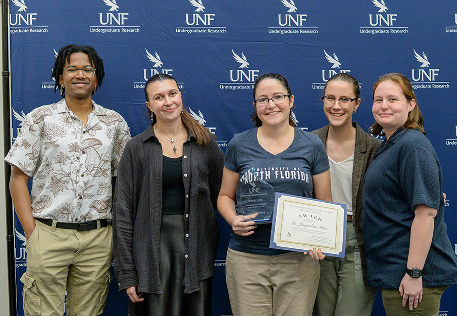 Dr. Jacqueline Meier holding her certificate standing among four other researchers