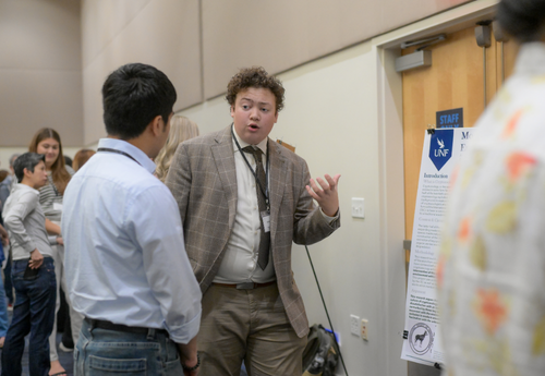 Student in blazer presenting research at UNF event