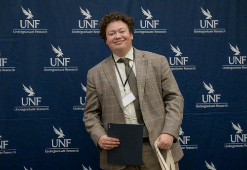 Man in blazer with award at UNF research event