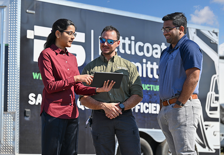 Alekhya Seelam showing laptop to a professor and Petticoat-Scmitt employee 