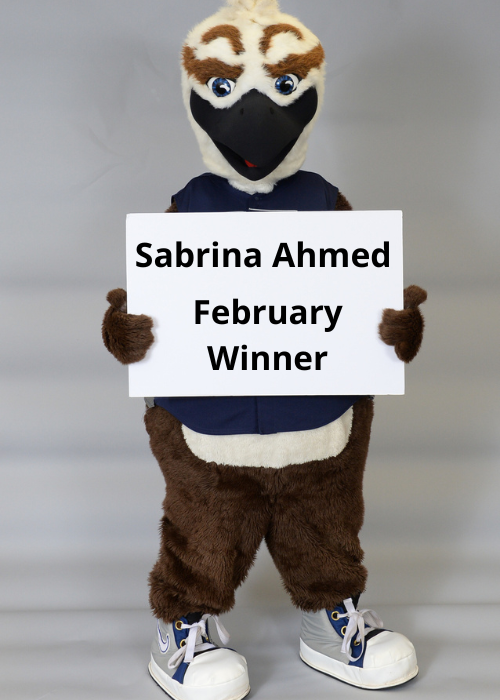 Ozzie Holding a sign that says 'Sabrina Ahmed February Winner'