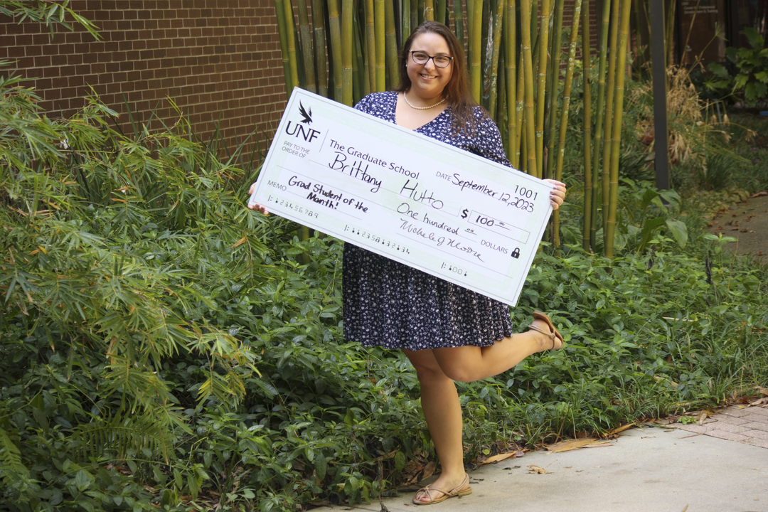 Grad Student of the Month holding check