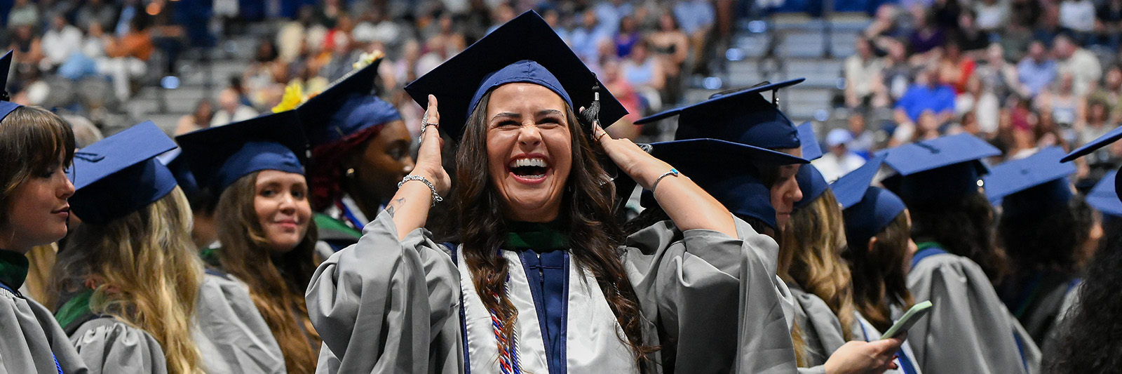 Students in cap and gown graduating and smiling