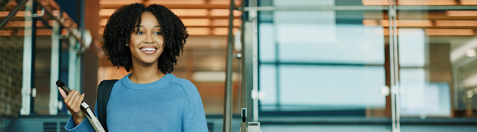 Student walking down library stairs with book in hand