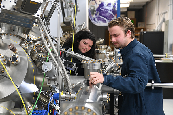 Two students working on a large machine