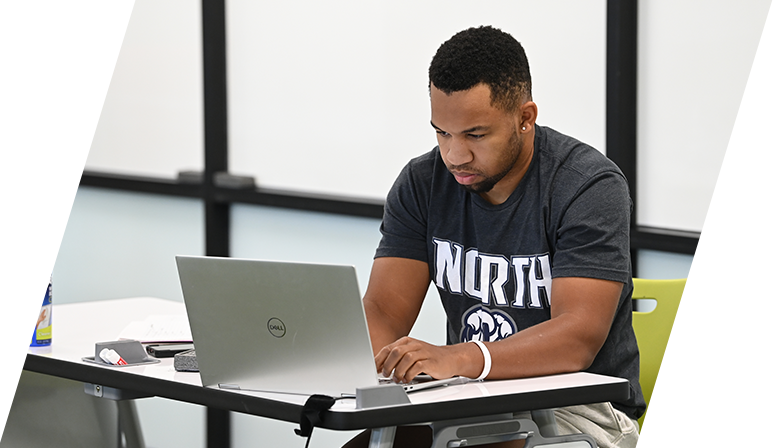 A student typing on their laptop in the library