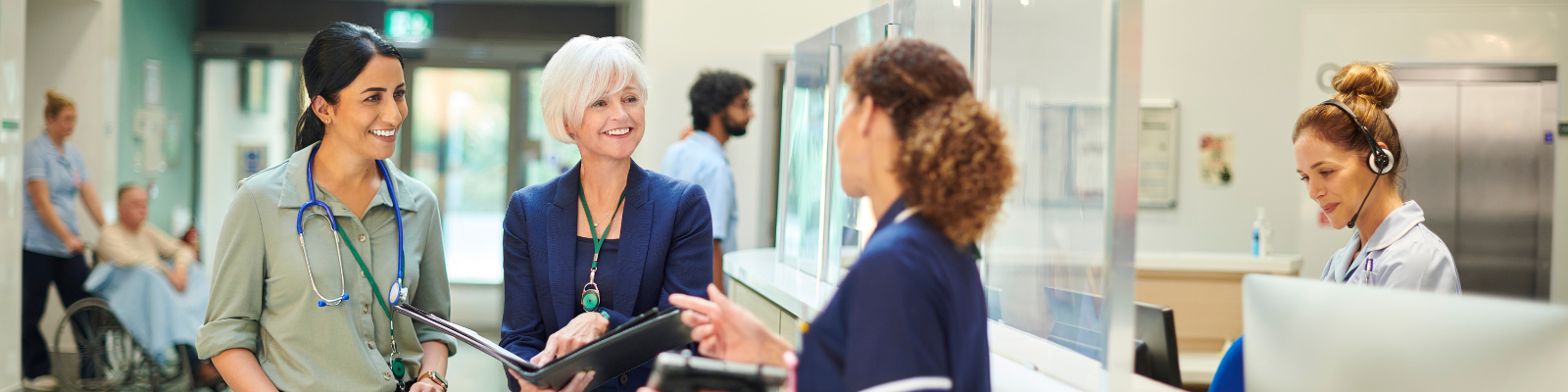 Three women in health administration talking in a hospital hallway