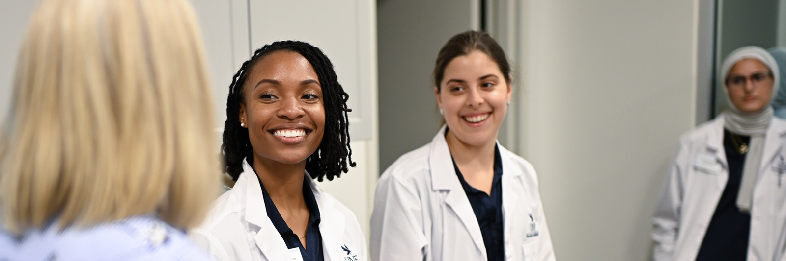 Three nursing students smiling and talking with a women