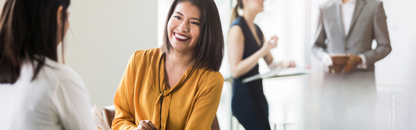 Women holding a clip board and talking with another women