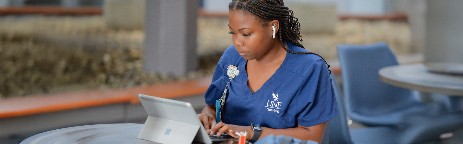 nursing student with a tablet sitting at a table