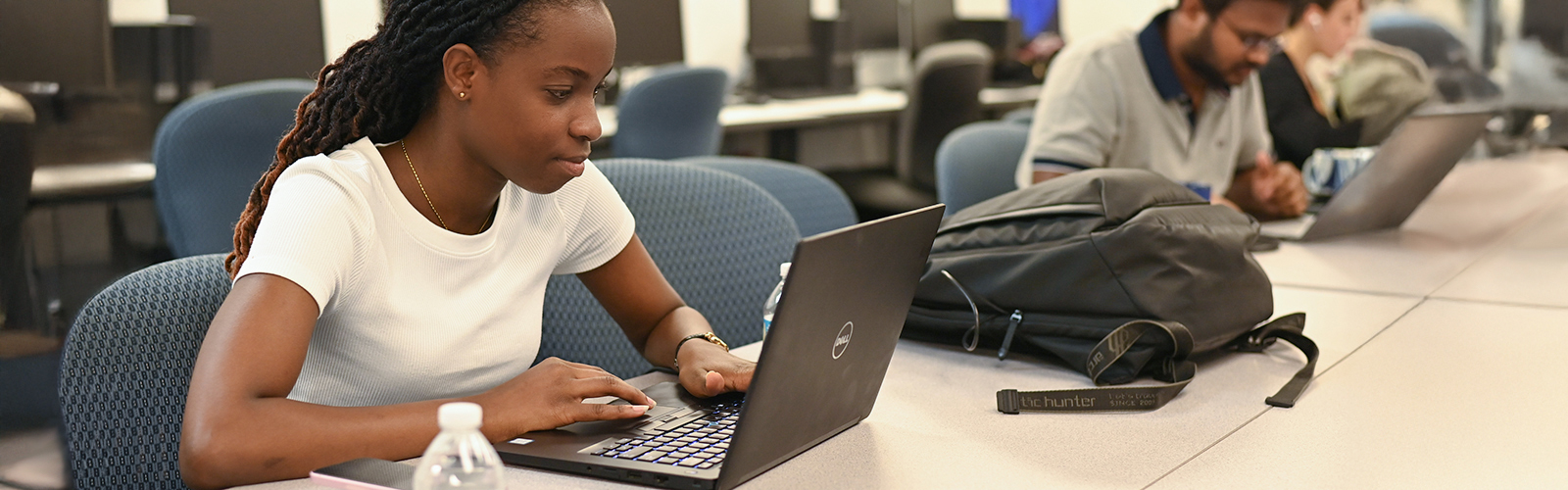 three graduate students working on laptops