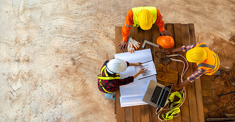 three civil engineers going over a blueprints on a table