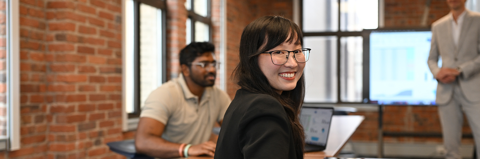 Three accounting students studying with one smiling at the audience