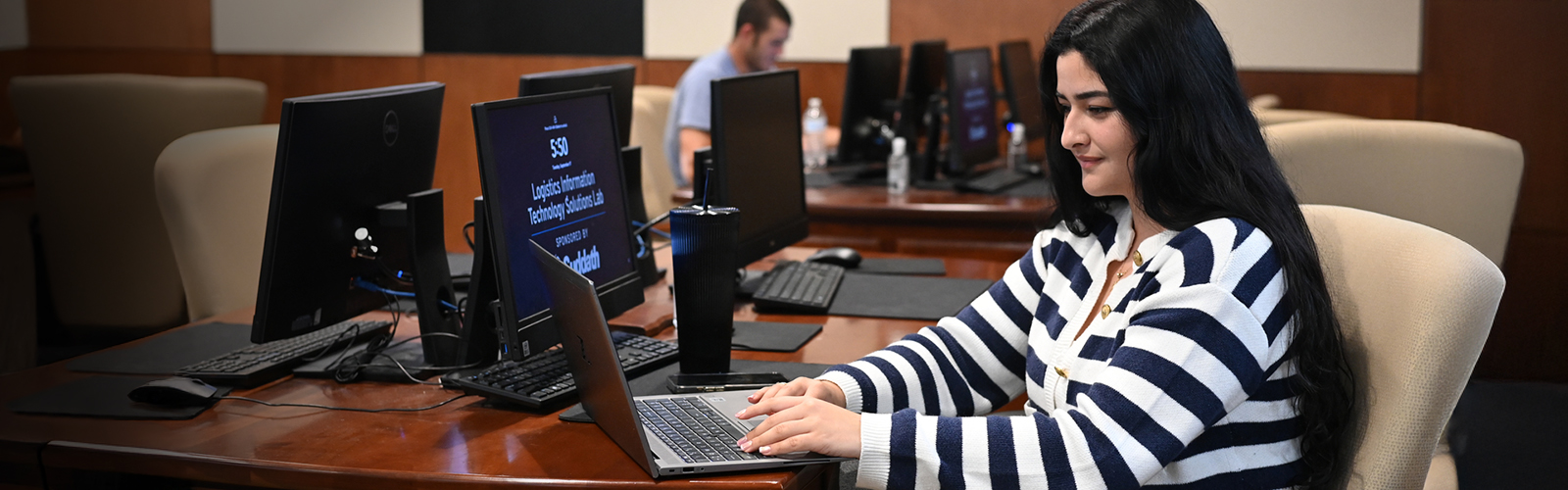 student in a logistics lab on a laptop