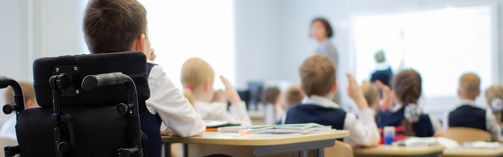 student in a wheelchair in a classroom with teacher and other students
