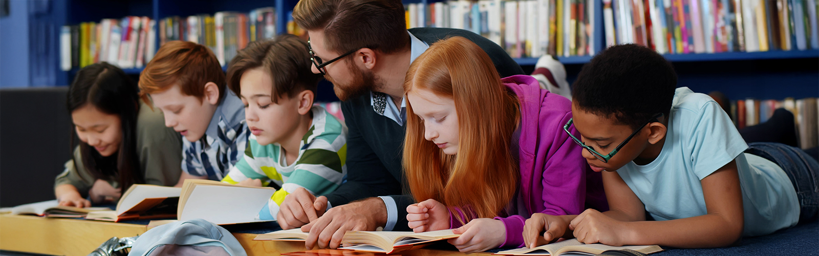 teacher reading with a group of students in a library