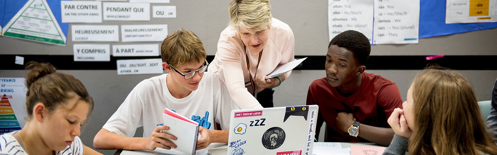 teacher helping her students on a laptop