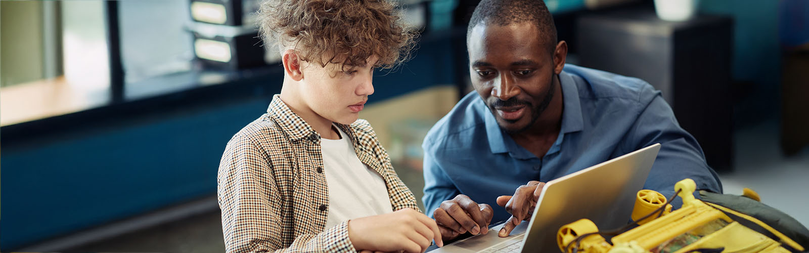 teacher and student working together on a laptop
