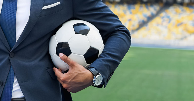 business man holding a soccer ball on a soccer field