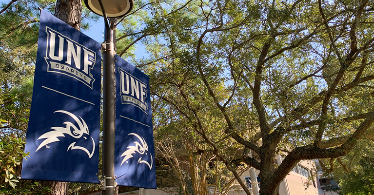 UNF Osprey banners on light post in front of trees
