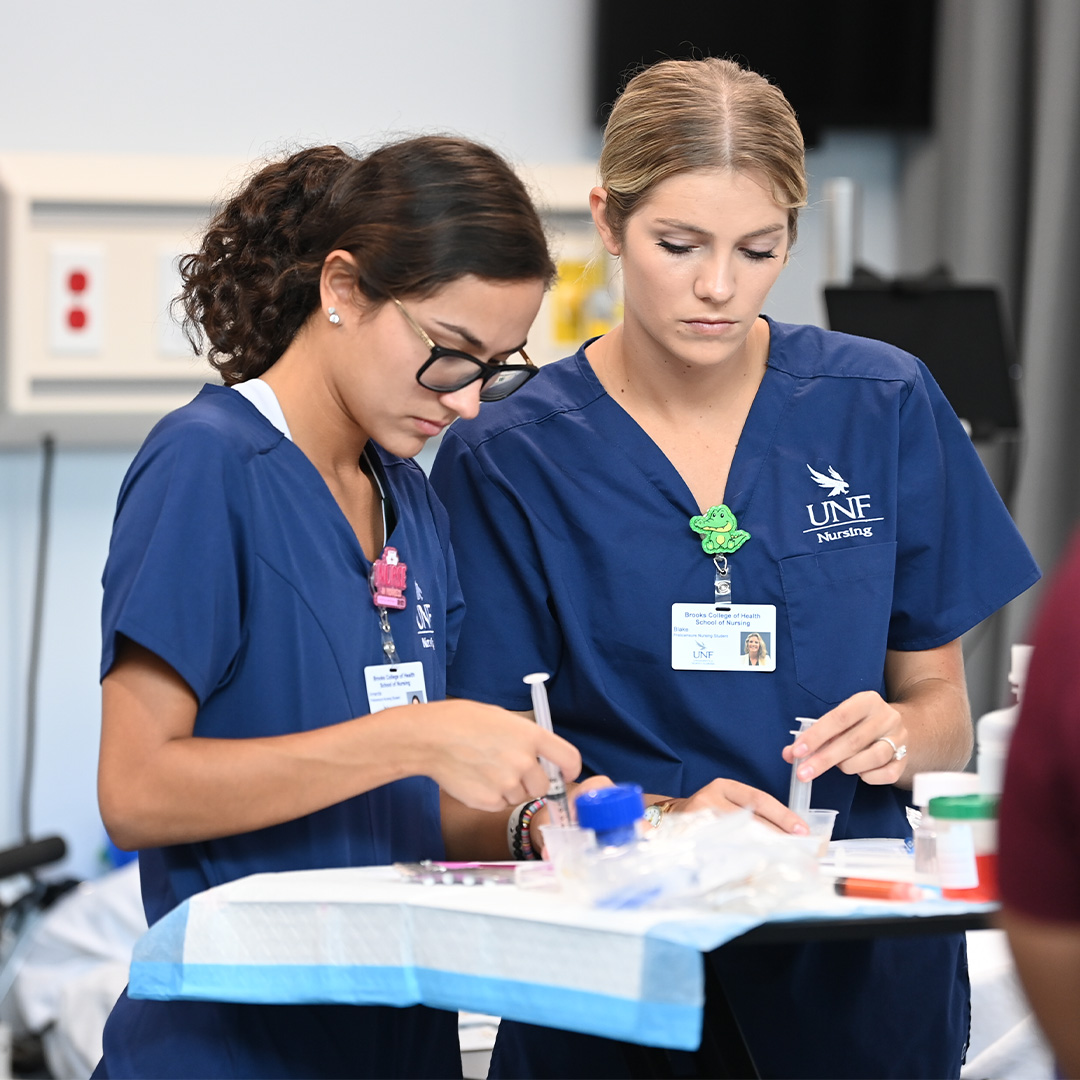 Two nursing students preparing syringes