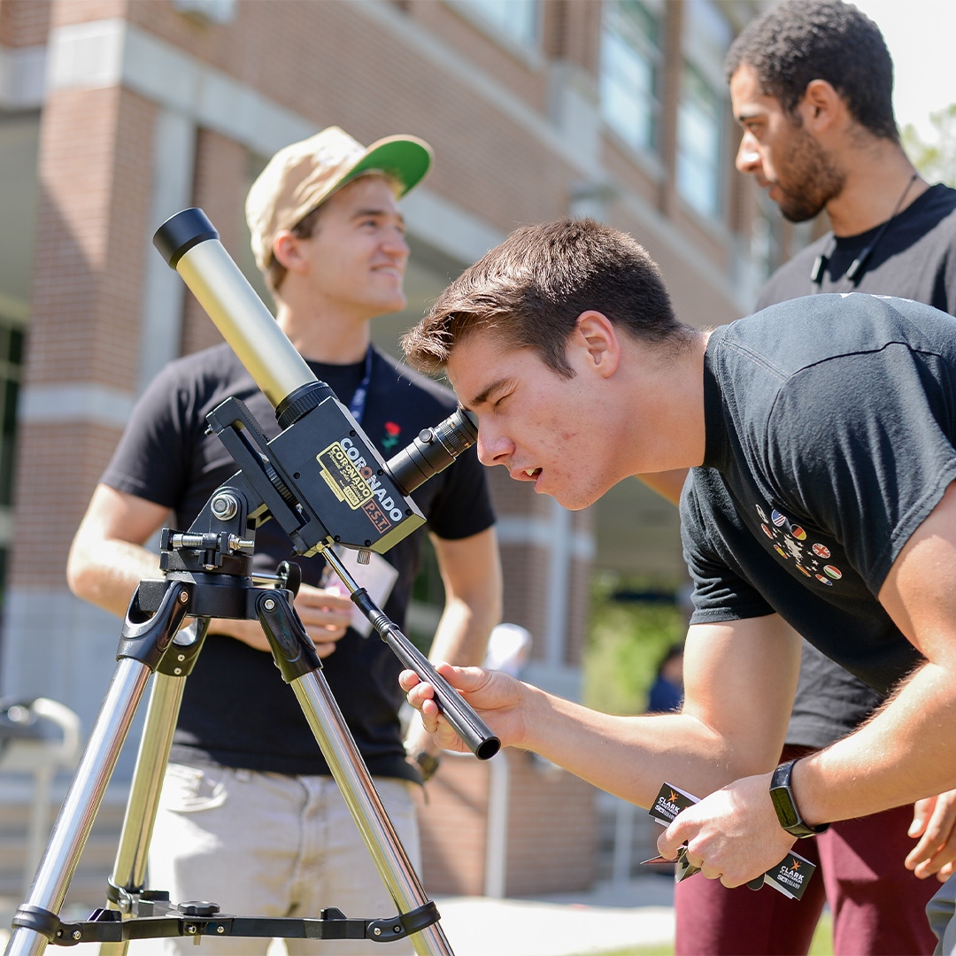 Student using solar telescope surrounded by two other students