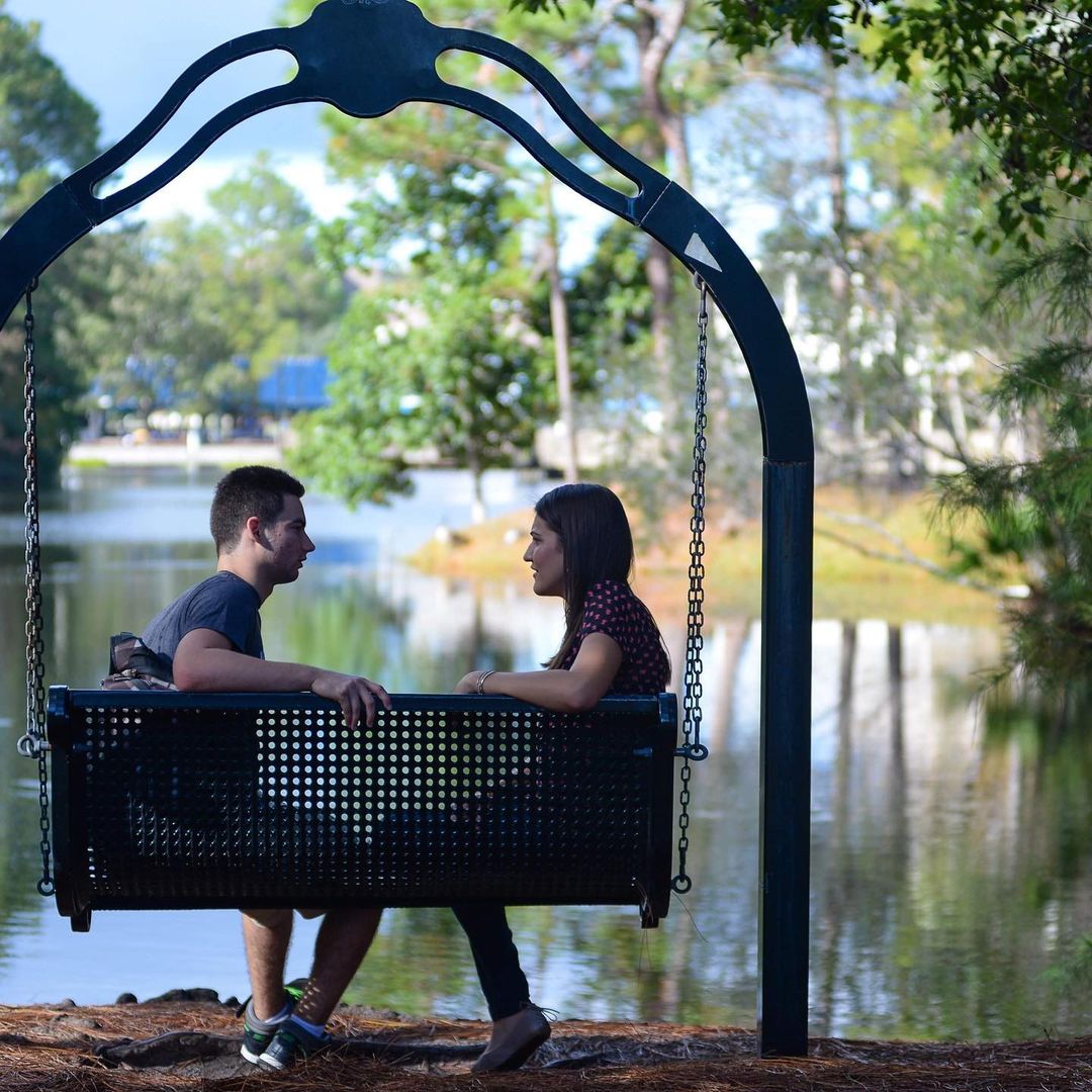 students sitting on swing by pond