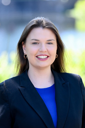 Portrait of a woman with dark hair and brown eyes with a blurry lake background.