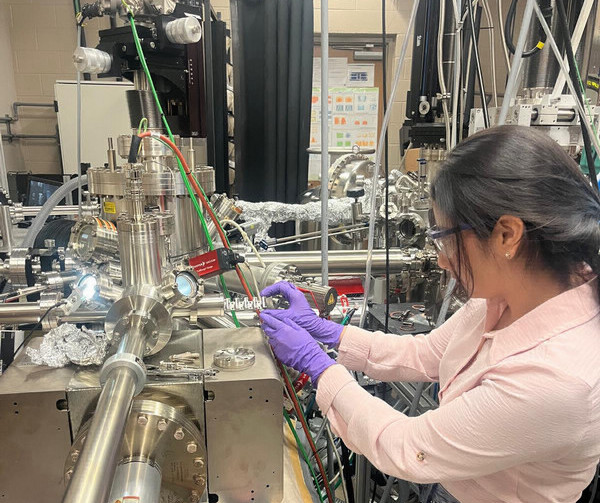 Student wearing purple gloves works in a lab.