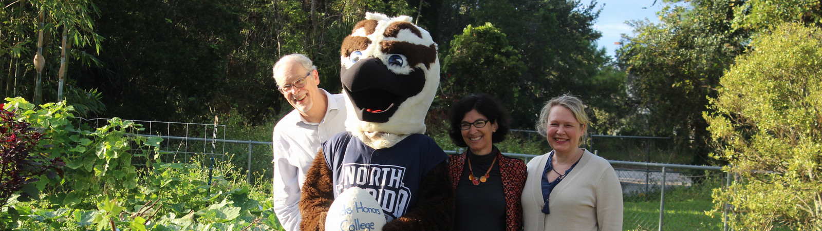 Honors faculty members stand in a giant stick nest with Ozzie the Osprey. 